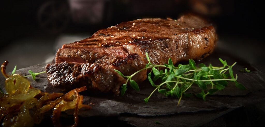 Fotografia aproximada de um farto e suculento bife de picanha com algumas fatias recortadas. 